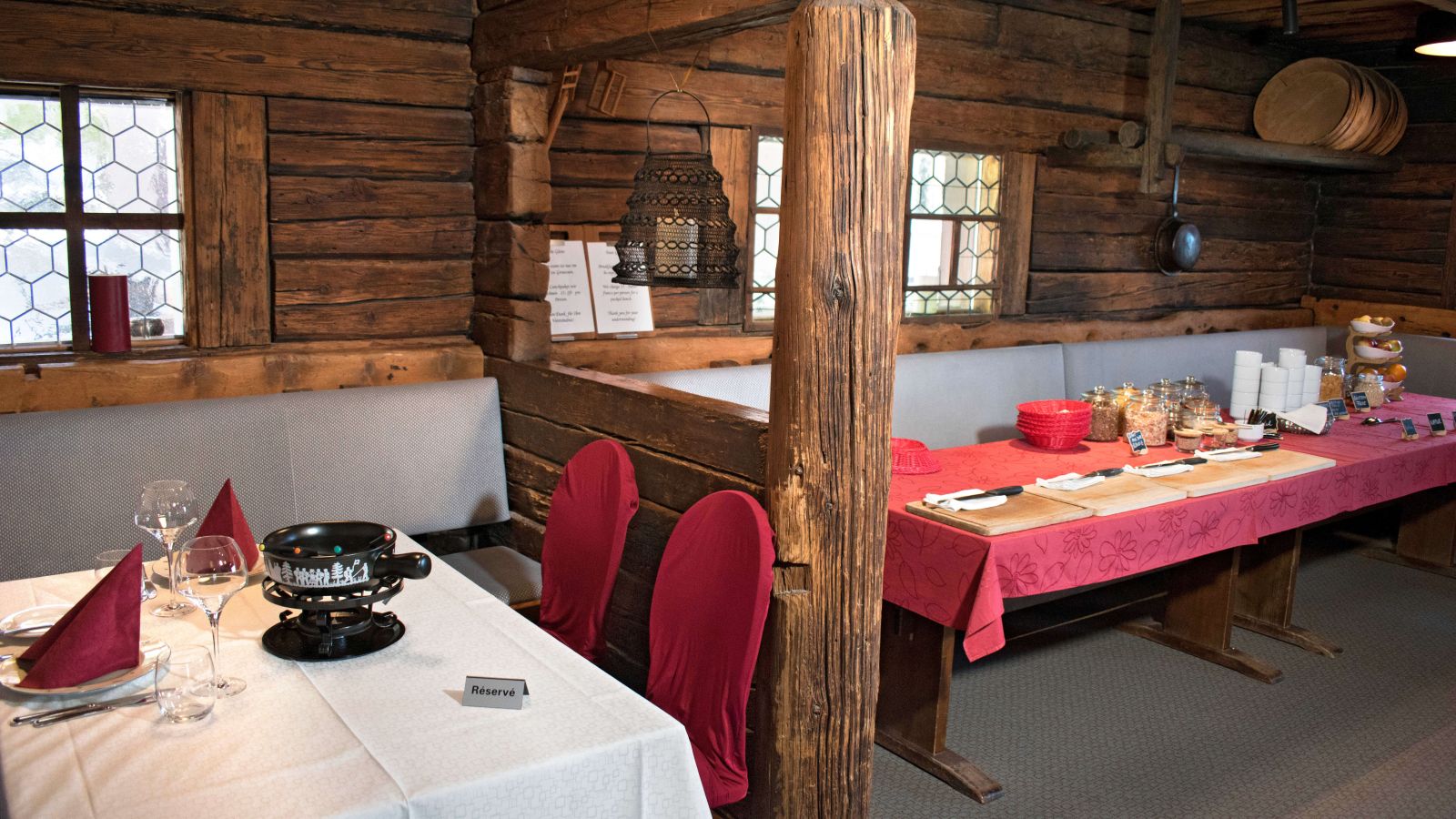 A cozy dining area featuring log walls and tables set for a meal.